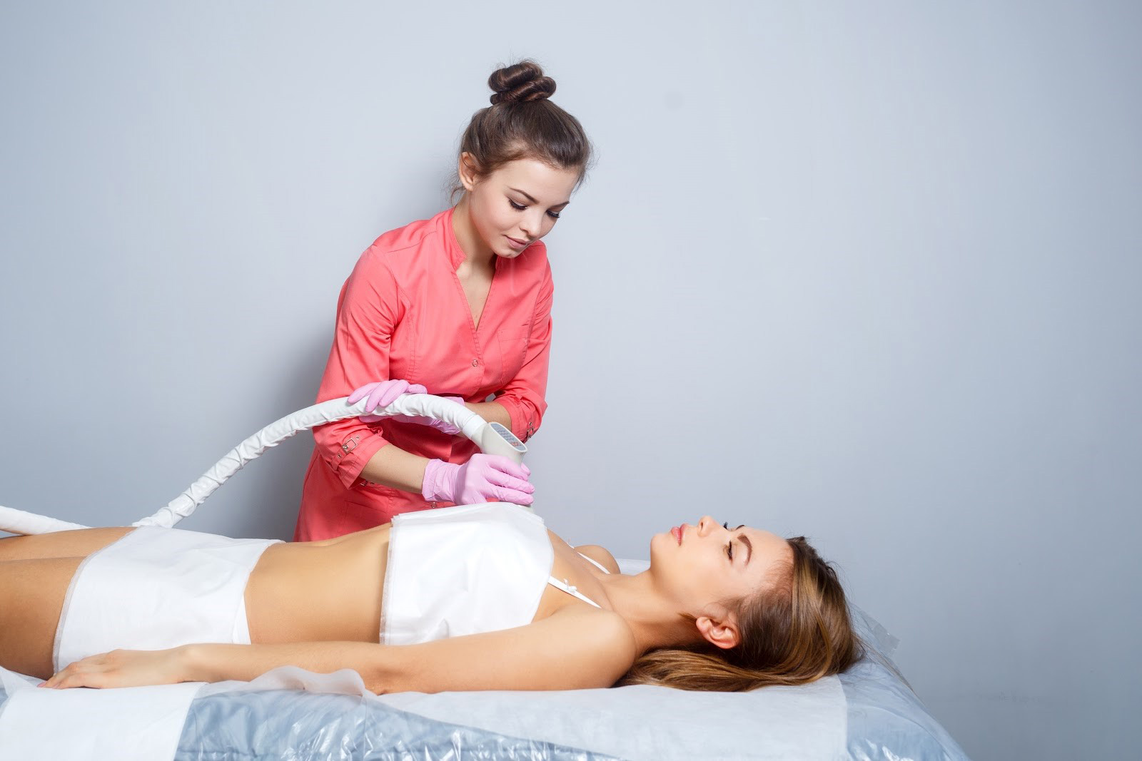woman laying peacefully while aesthetician performs CoolSculpting procedure