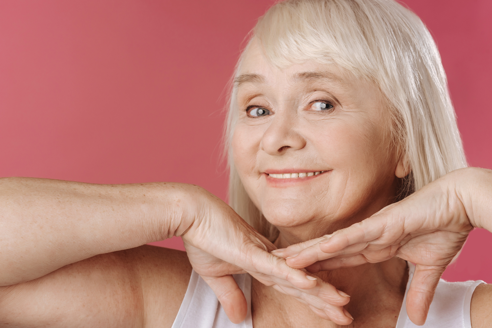 Older Woman Smiling With Hands Under Face